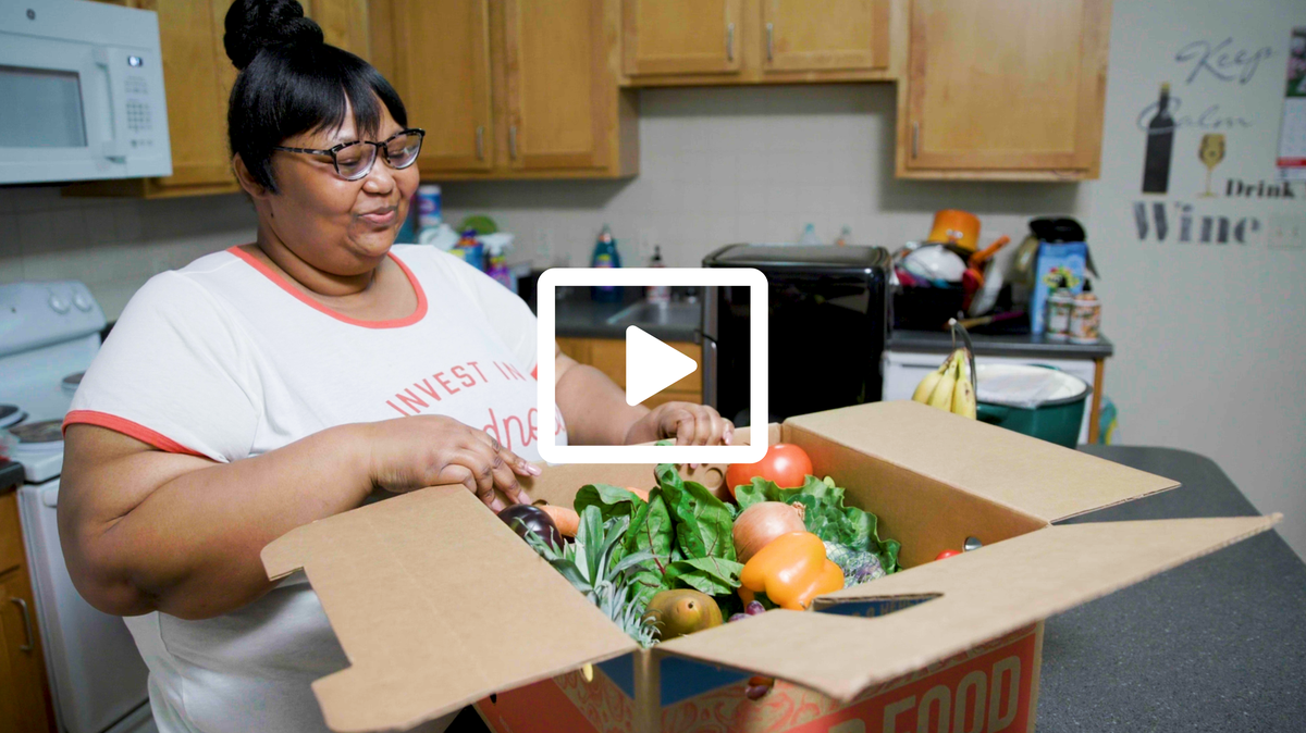 Good Food for All participant looking at a box filled with produce