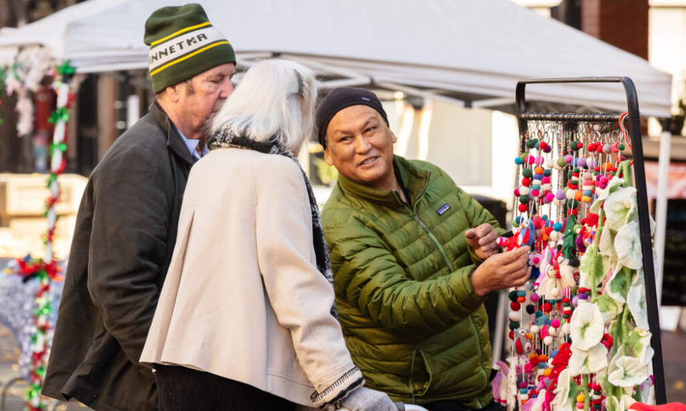 Vendor showing wool garlands to two people