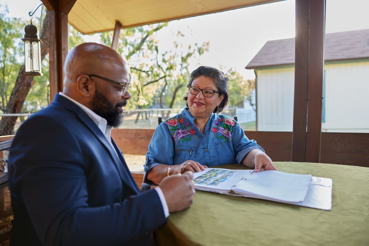 two people sitting together at a table looking at photos of homes