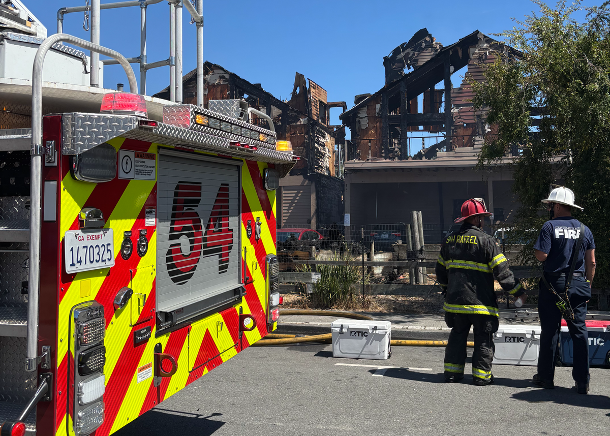 Fire engine in front of burnt building with two firefighters