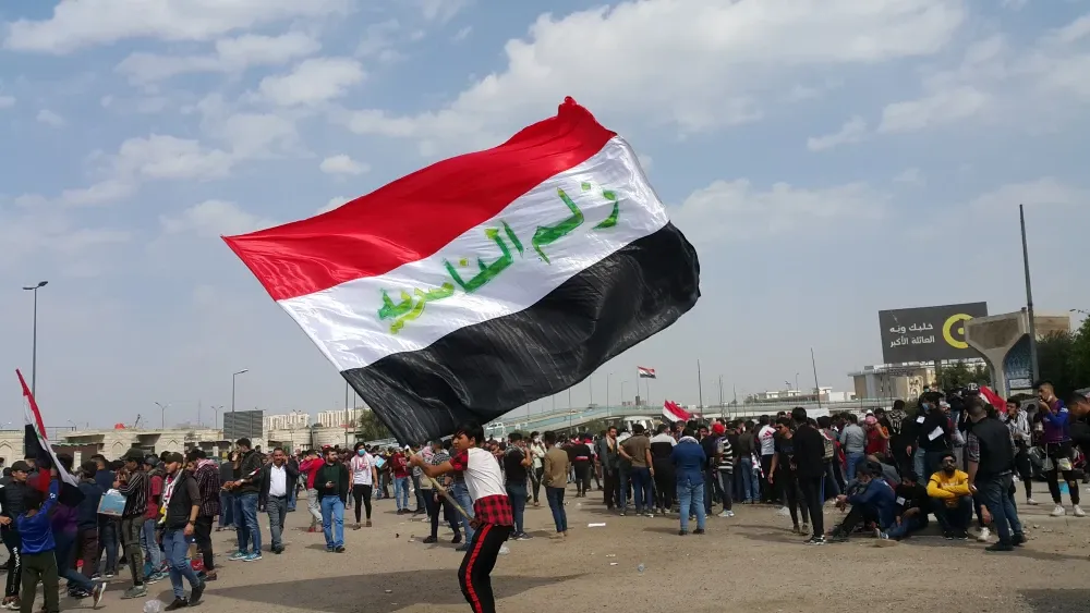 A man waves the flag of Iraq, with 