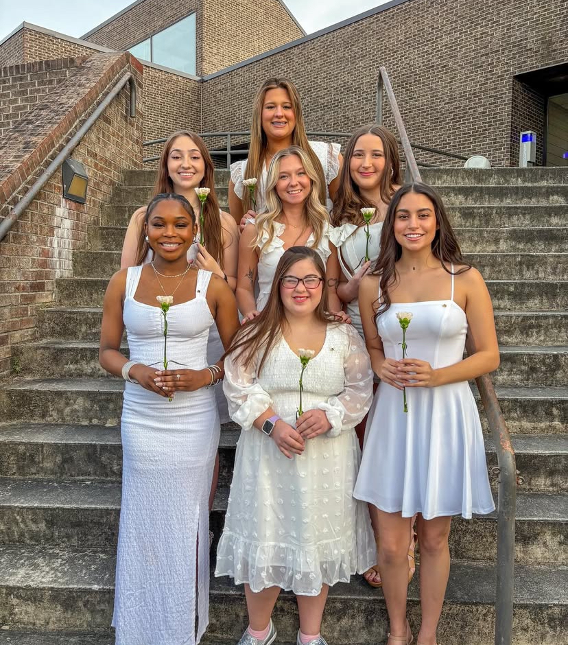USC Aiken students posing with roses in white dresses as part of sorority membership activities.