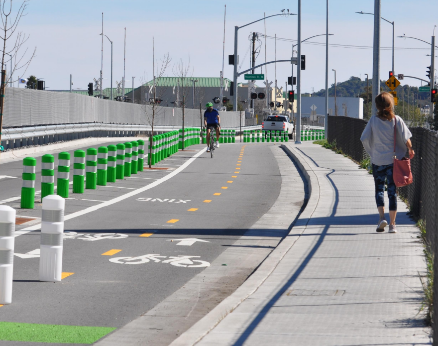 Person walking on sidewalk next to a bike lane