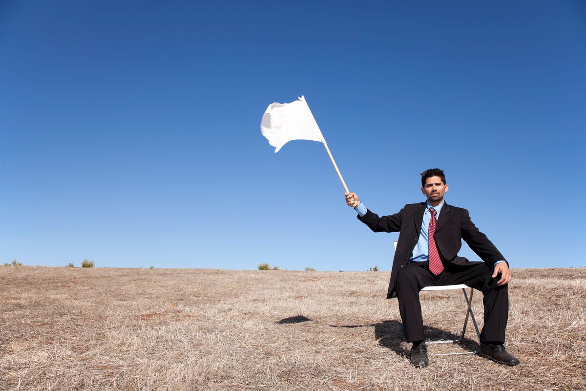 A man in a suit waves a white flag of surrender.