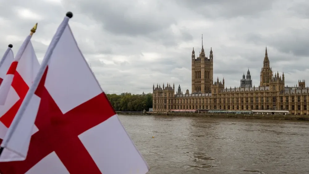 The flag of St. George files across the Thames from the Houses of Parliament in London. For those flying it today, the flag represents pride in being English—reclaiming a symbol of national unity, her...
