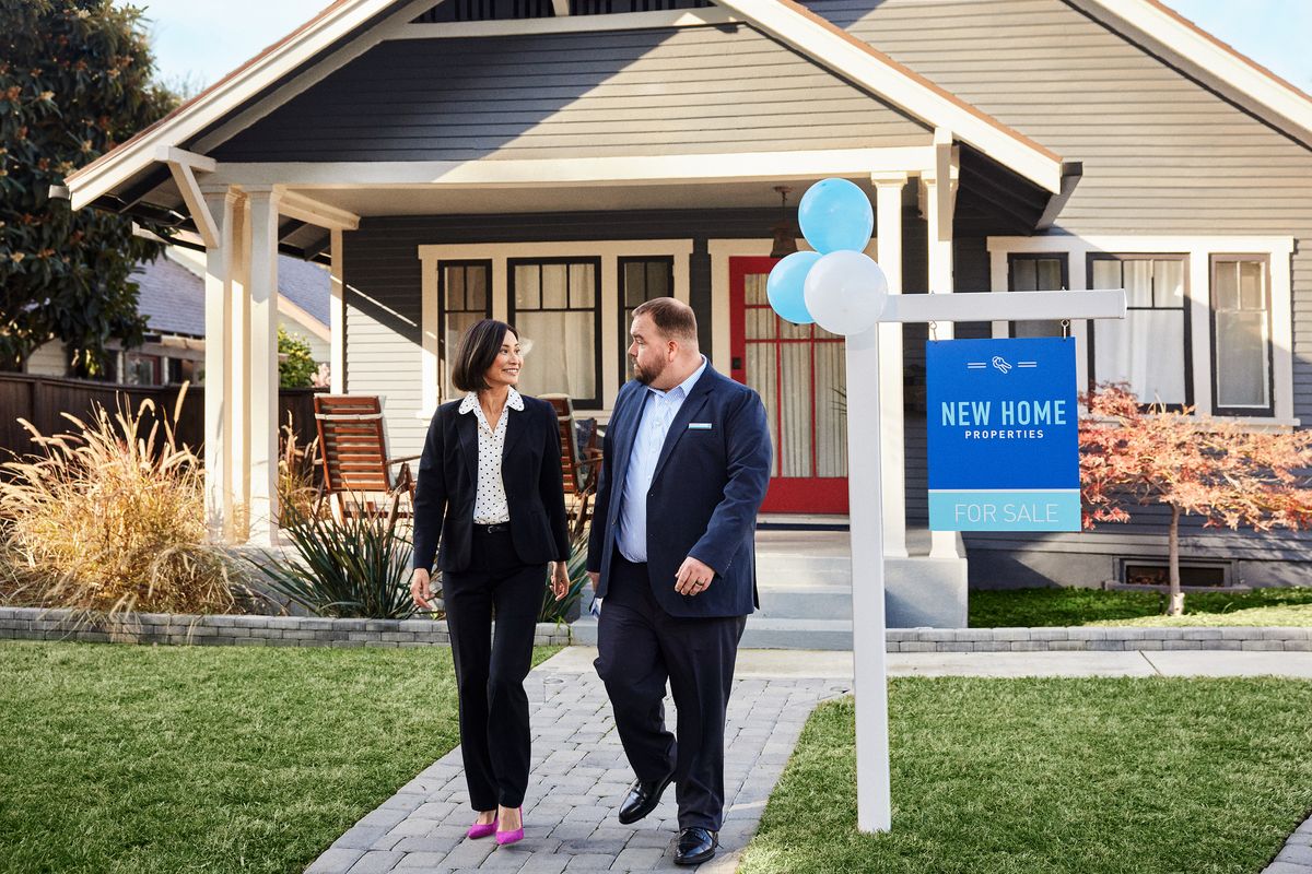 two people standing outside a home that is for sale