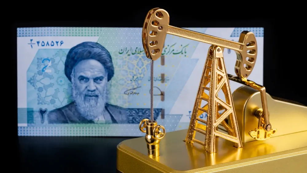 An Iranian banknote with a portrait of Ruhollah Khomeini and a gold model of an oil pump.  Shutterstock