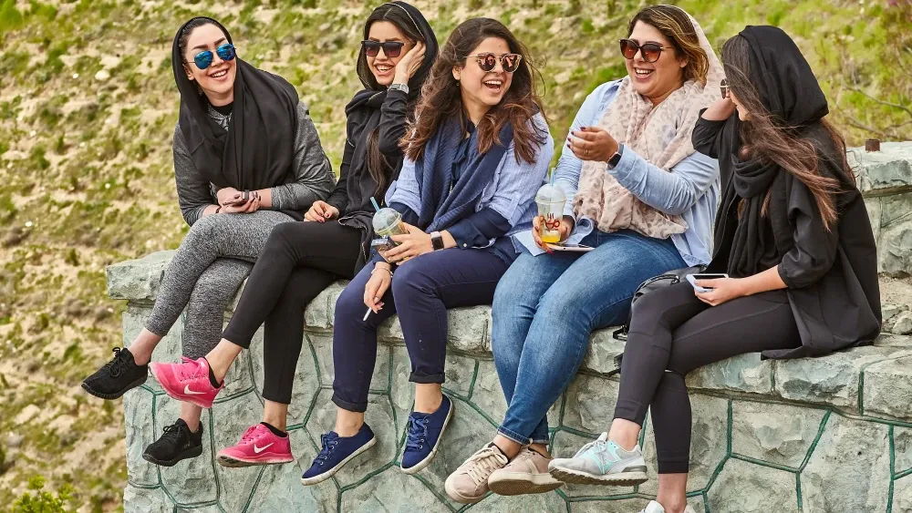 Young Iranian women in a park in Tehran, including one without a hijab. Shutterstock