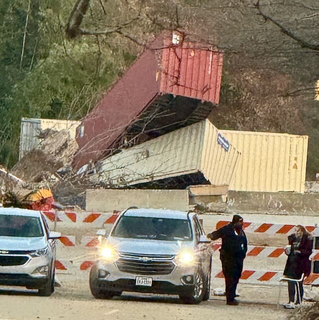 Picture of a barricaded road with storage trailers stacked on top of each other behind the barrier