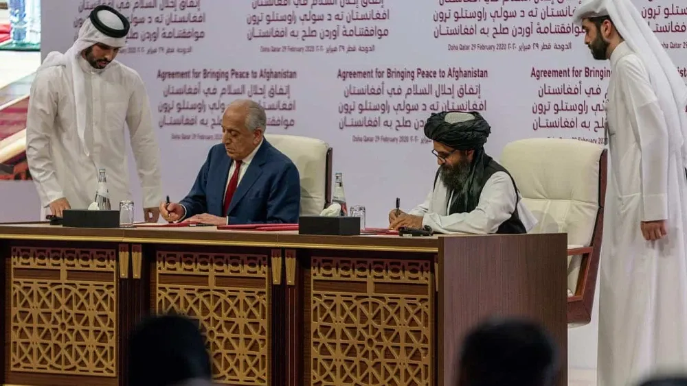 Zalmay Khalilzad, U.S. Special Representative for Afghanistan Reconciliation (left), and Taliban representative Abdul Ghani Baradar (right) sign the agreement to bring peace to Afghanistan in Doha, Qa...