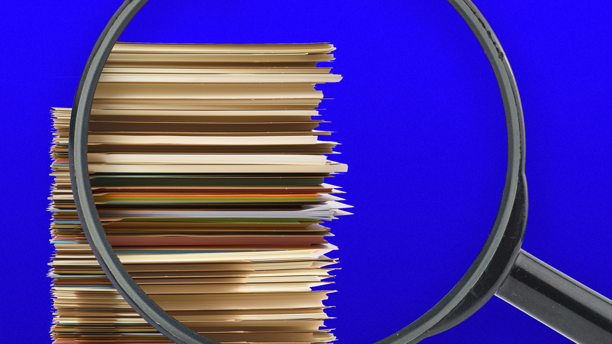 A magnifying glass viewing a stack of folders.