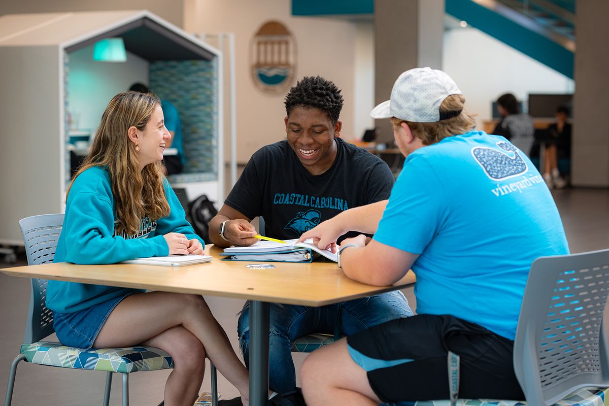 CoastalLIFE students laugh together while completing academic work.