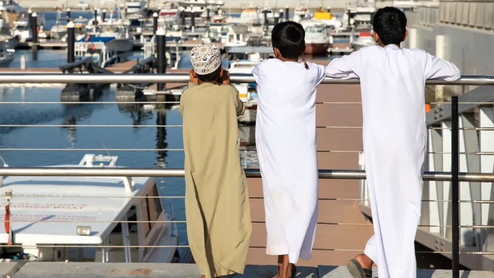 Omani youths in dishdasha at the marina in Al Mouj, The Wave, Muscat, Oman.  Shutterstock
