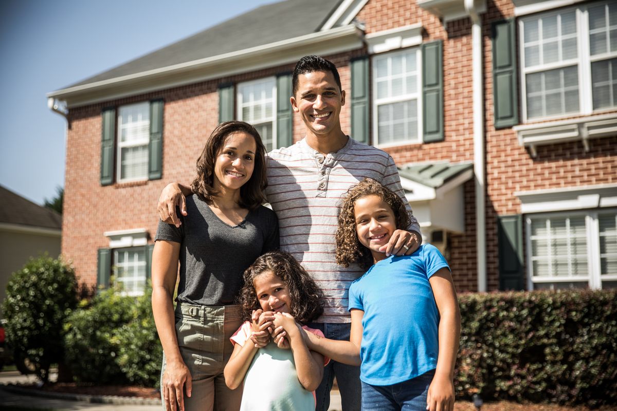 a family of four standing in front of a house