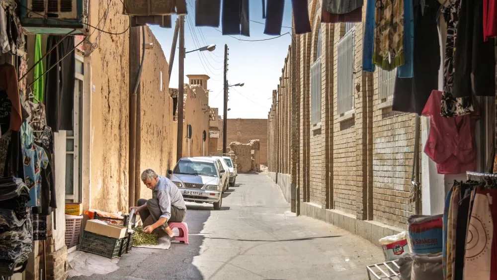 A man prepares herbs for sale on a street in the Old City of Yazd, Iran.  Shutterstock