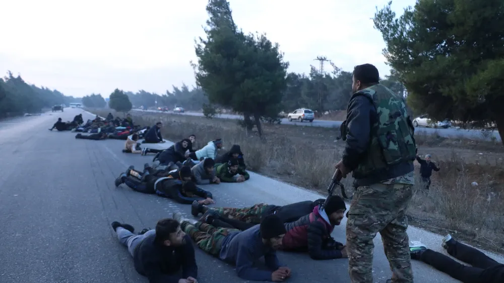 Victorious HTS troops hold pro-Assad soldiers captive on a highway. Shutterstock
