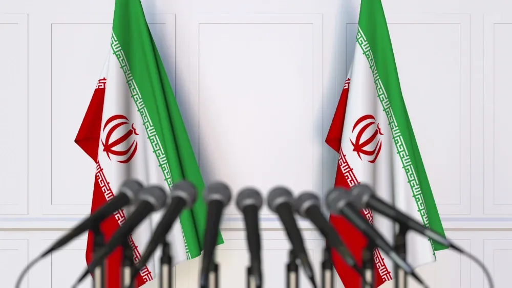 Iranian flags are posted at a podium set up for a news conference.  Shutterstock