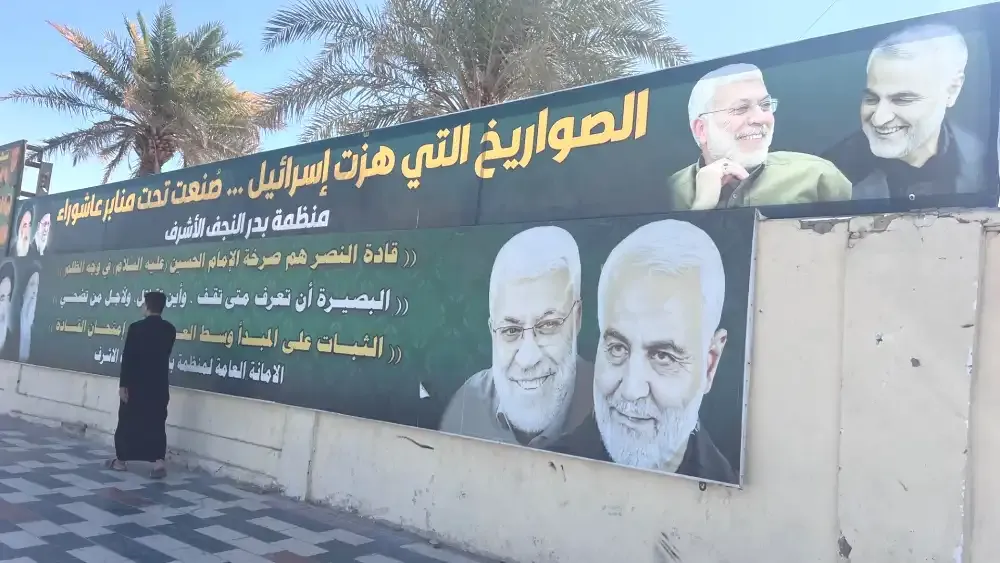 Outside Badr's Najaf, Iraq, office. The top poster reads: 