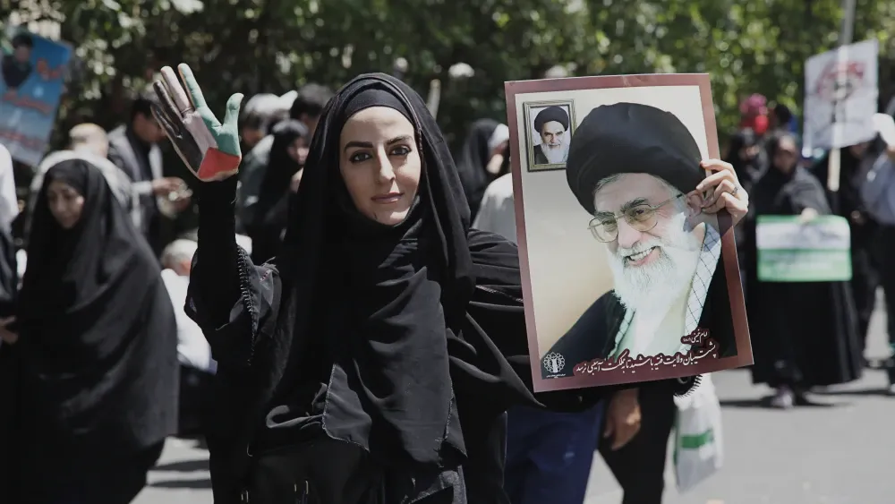 A woman carries a poster of Supreme Leader Ali Khamenei in Tehran, Iran. Shutterstock
