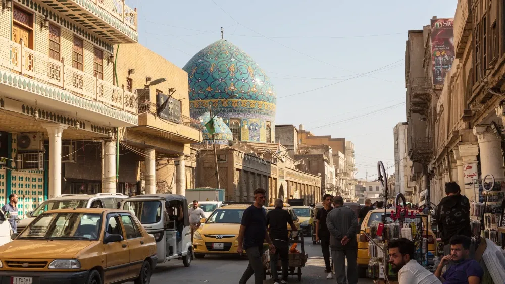 The blue dome of Haydar Khana Mosque rises above this street in Baghdad, Iraq.  Shutterstock