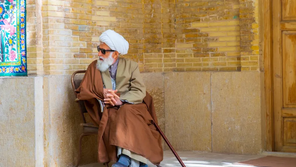 An ayatollah sits outside a religious school in Shiraz, Iran. Shutterstock
