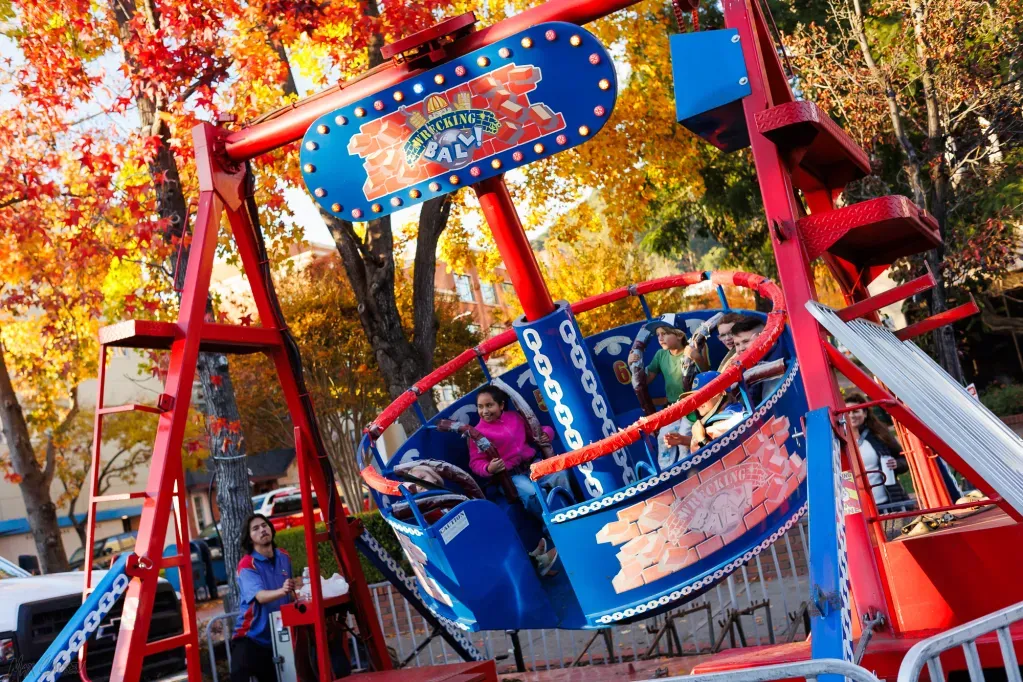 Smiling children on a carnival ride with fall foliage