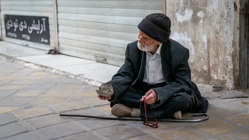 An old man begs in the street in Iran. Sixty percent of Iranians live below the poverty line.  Shutterstock