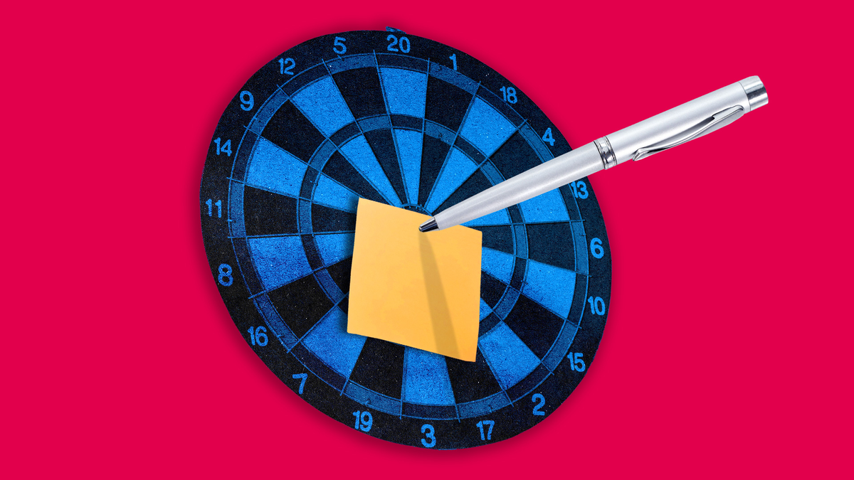 A pen on a post-it note, on top of a dartboard.