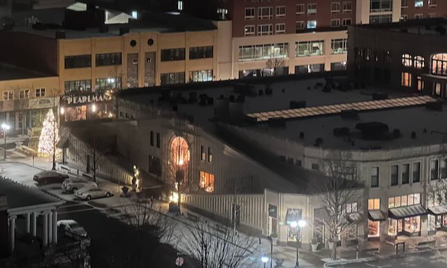 a night time picture of the Grove Arcade art deco building in Downtown Asheville beside a lit Christmas tree covered in snow